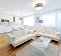 A spacious living room with white sofas and an open kitchen in a 3-room apartment.
