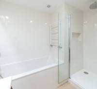 Bathroom in a 3-room apartment with a bathtub, shower corner, and white tiles.