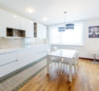 A kitchen in a 3-room apartment with a dining table, white furniture, and a picture of the Eiffel Tower.