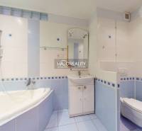 A bathroom in a 3-room apartment with light blue tiles, a bathtub, and a sink.