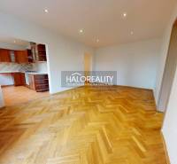 A spacious living area in a 3-room apartment with parquet flooring and a kitchen.
