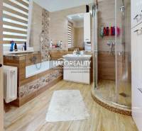 A bathroom in a family house with a bathtub, shower, and sink, warm wood tones.