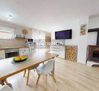 A kitchen in a family house with a dining table, a fireplace, and firewood.