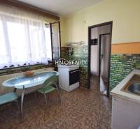 A kitchen in a family house with a light table, chairs, and brick cladding on the walls.