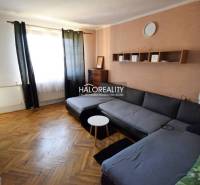 Living room with a corner sofa, table, and parquet floor in a family house.