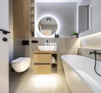 A modern bathroom with a bathtub, mirror, and toilet in a 3-room apartment on Benediktiho Street.