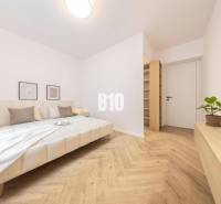 Bedroom in a 3-room apartment with a double bed, light walls, and wooden flooring.