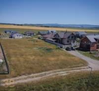 Plots - housing in Mlynica, surrounded by houses and fields, with a rural scenery.