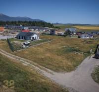 Plots - housing in Mlynica with a view of the mountains, surrounded by houses and construction activity.