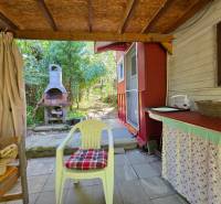 Terrace of a cottage with a plastic chair and a grill in the village of Nemce surrounded by greenery.