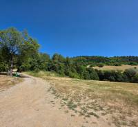 A winding country road in nature near Nemce, surrounded by greenery and a clear sky.