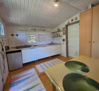 The interior of a cabin with light wooden paneling, a kitchen unit, and a table with a print.