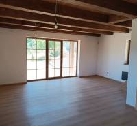 The interior of a cabin with wooden beams and large windows, bright spaces.