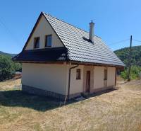 A cottage in Horné Hámre with a metal roof and surrounding nature, under a blue sky.