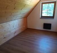 Attic room with wooden paneling and a view from the window in the cabin.