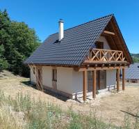 A cottage in Horné Hámre with a wooden balcony, surrounded by nature and lush greenery.