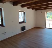 The interior of the cottage with light walls, wooden beams, and large windows for natural light.