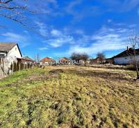 A plot for residential use in Veľké Ludince with neighboring houses and a grassy area.