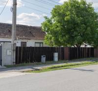 A house with a wooden fence and a tree on Športová Street in Gajary, residential plots.