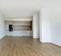 A kitchen in a 3-room apartment with wooden flooring and a light kitchen unit.