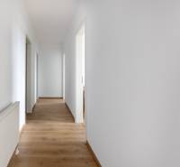 A hallway in a 3-room apartment with white walls and wooden flooring.