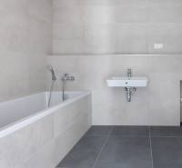 A bathroom with a bathtub and a sink in a 3-room apartment with neutral tiles.