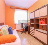 A room in a 3-room apartment with orange walls, a sofa, a table, and cabinets.