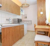 A kitchen in a 3-room apartment with wooden furniture, a stove, and a microwave oven.