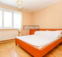 Bright bedroom in a 3-room apartment with a bed, wooden floor, and curtains.