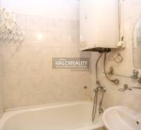 Bathroom with a bathtub and a boiler in a 3-room apartment, white tiles, sink.
