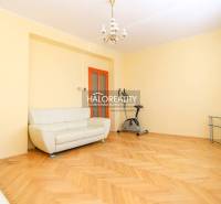 A bright living room in a three-room apartment with a sofa and an exercise bike.