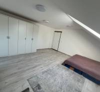 Bedroom in a family house with a sloped ceiling, a bed, opposite a large wardrobe.