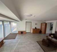 The interior of a family house with large windows, tiles, and wooden furniture.