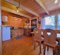Interior of a cabin with wooden furniture and a kitchen area, with a view of the surroundings.