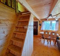 Wooden interior of a cabin with wooden stairs, a table, and comfortable seating.