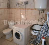 Bathroom in a family house with a washing machine, toilet, and sink.