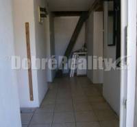 A hallway in a family house with white walls and ceramic tiles.