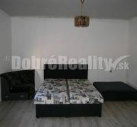 A bedroom in a family house with a bed, a sofa, and a wooden floor.