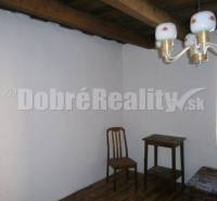 A simply furnished room in a family house with a wooden ceiling and floor.