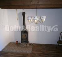 Interior of a family house with a stove, wooden chair, and wall lamp.