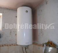 An electric boiler in a family house with wall cladding and a small window.