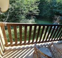 View from the cabin in Kvakovce at Dobrá, wooden railing, greenery, terrace chairs.