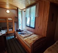 The interior of a cabin with a bunk bed, simple furniture, and a wooden ceiling.