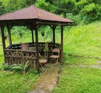 Wooden gazebo with seating in the middle of greenery near the cottage on Dobrá Street in Kvakovce.