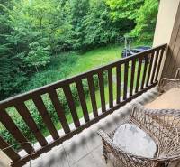The balcony of the cottage with wicker chairs and a view of the garden and greenery.
