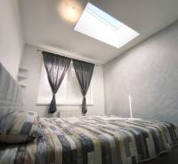 Bright bedroom in a 2-room apartment with a bed, large window, and skylight.