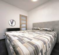 Bedroom in a 2-room apartment with a large bed and a mirror on white walls.