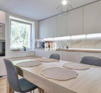A kitchen in a family house with a dining table, built-in appliances, and a large window.