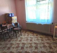 A room in a family house with a carpet pattern and a table with chairs.