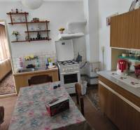A kitchen in a family house with a dining table, a countertop, and decorations on the shelf.